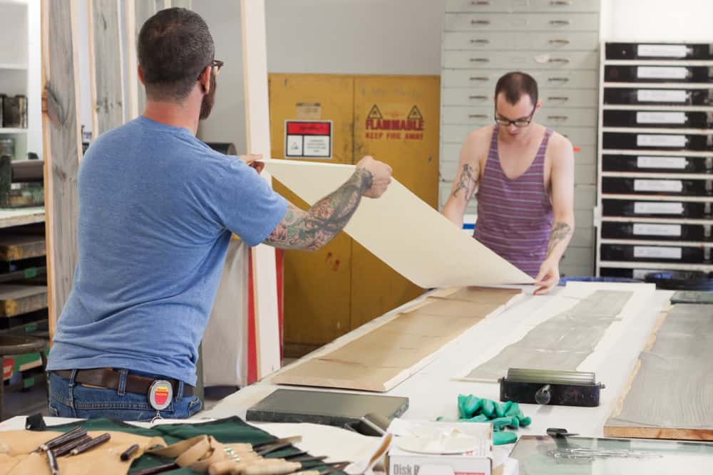 Nick and Miles lay the paper down to create a print