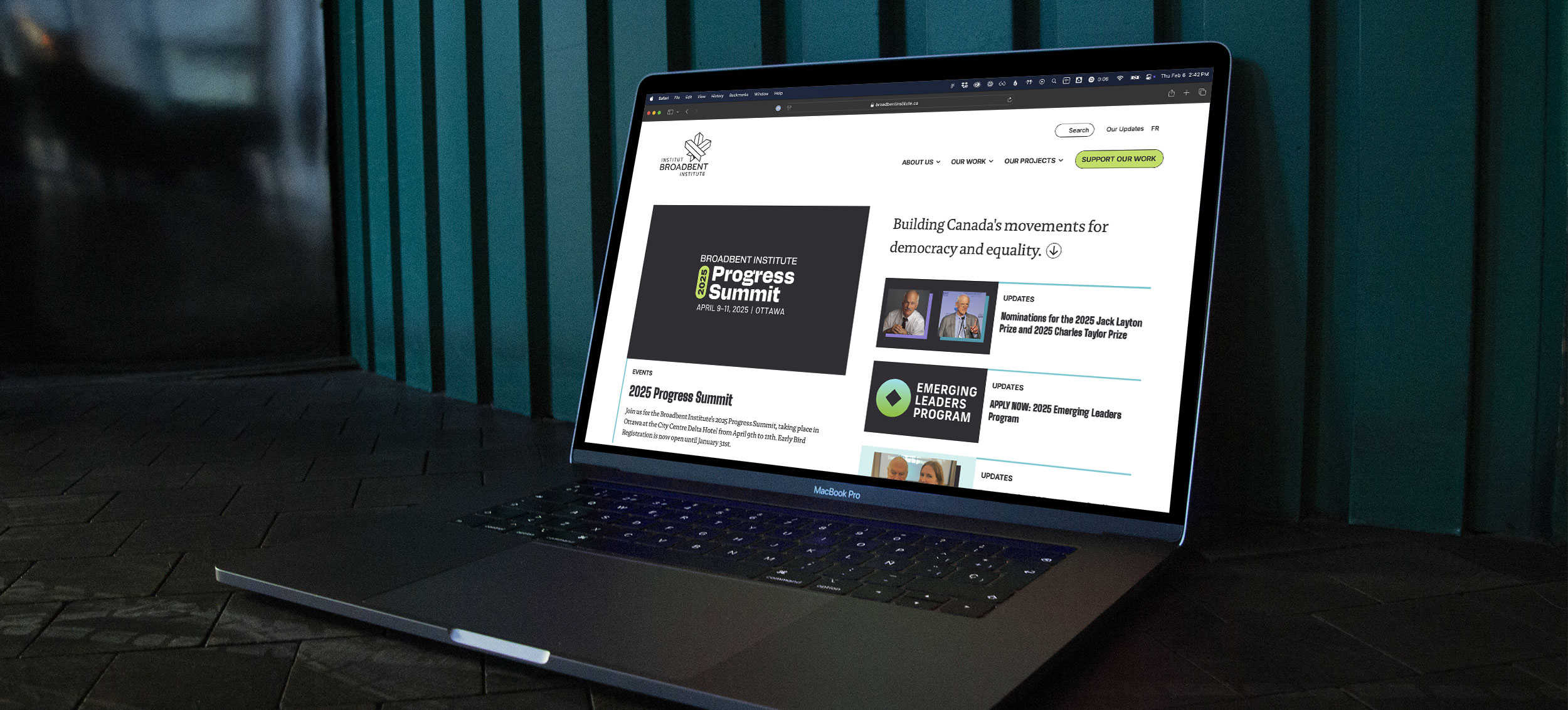 Home page of the Broadbent Institute website shown on a Macbook Pro sitting on the floor.